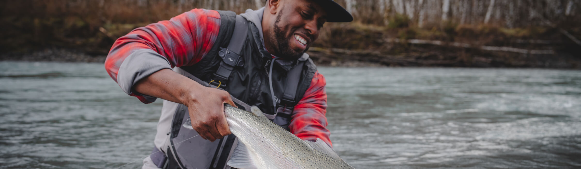 Lael Johnson in the river admiring the steelhead he just caught.