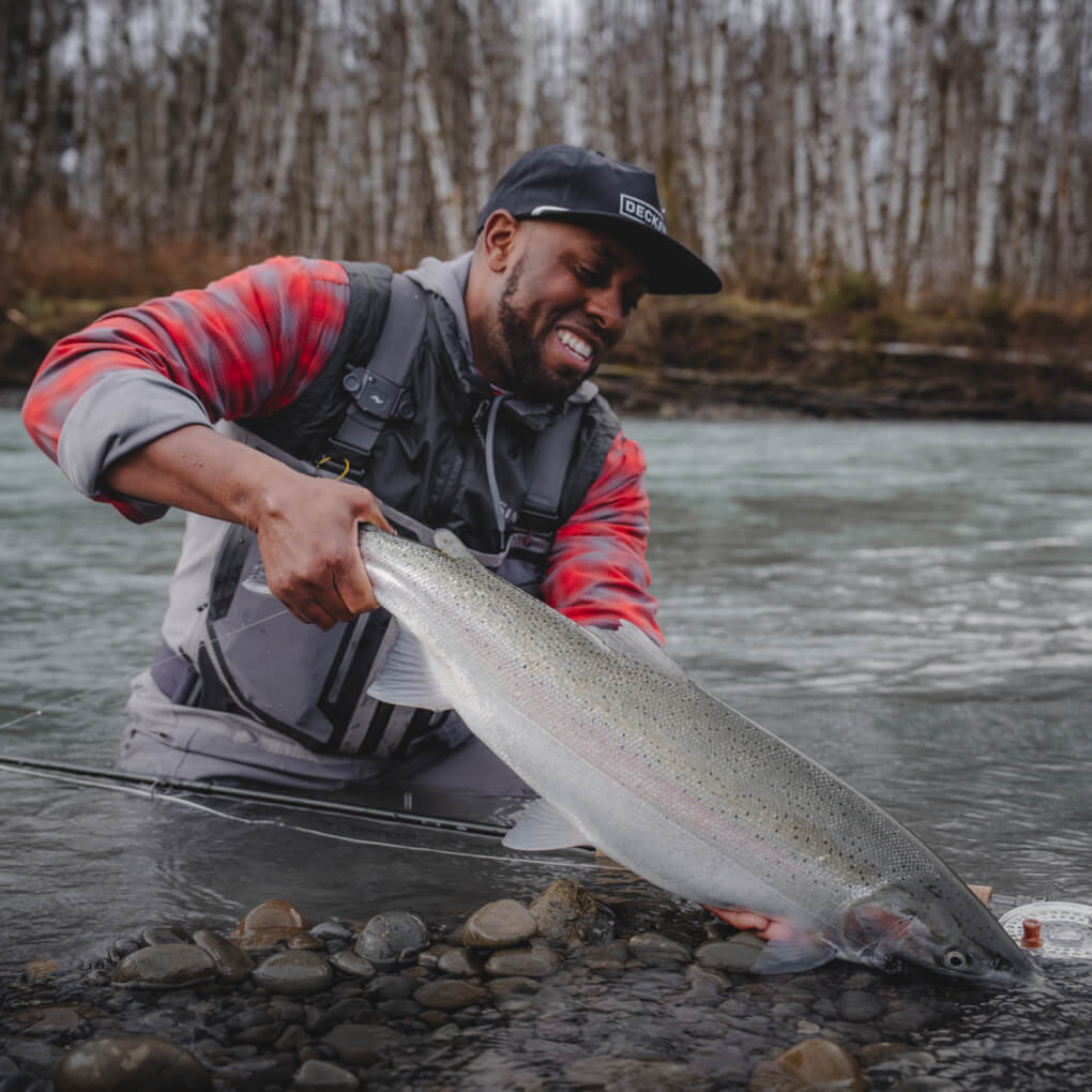 Lael Johnson in the river admiring the steelhead he just caught.