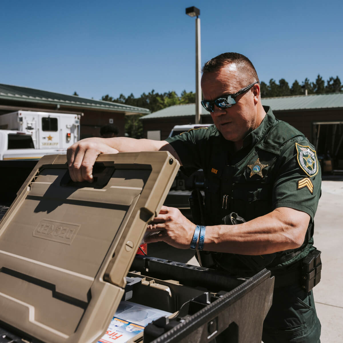 A sheriffs officer getting gear out of a d-co case in his vehicle's drawer system.