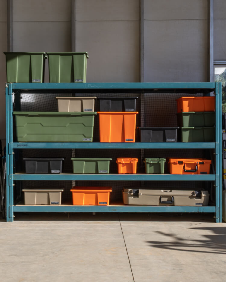 Storage shelves with colorful Payloader bins and protective cases in a garage setting