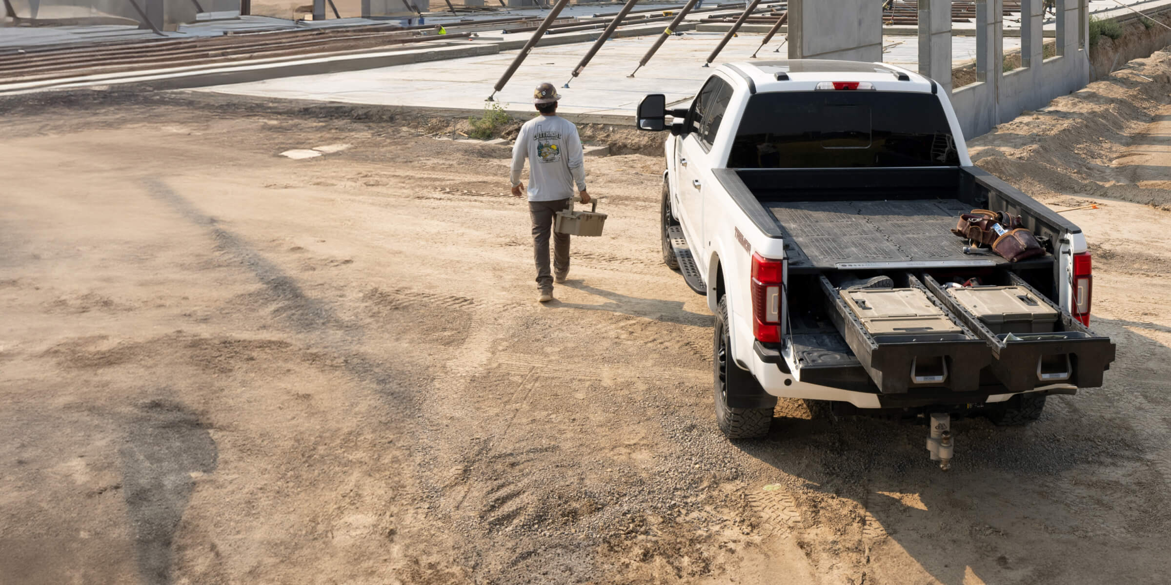 A man carrying a D-co case away from his truck with a Drawer System at a jobsite.