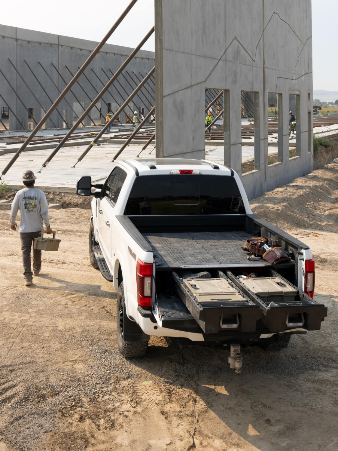 A man carrying a D-co case away from his truck with a Drawer System at a jobsite.