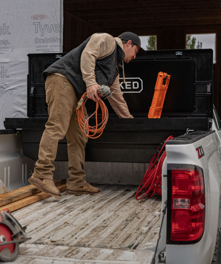 A man retrieving tools from his truck's tool box.