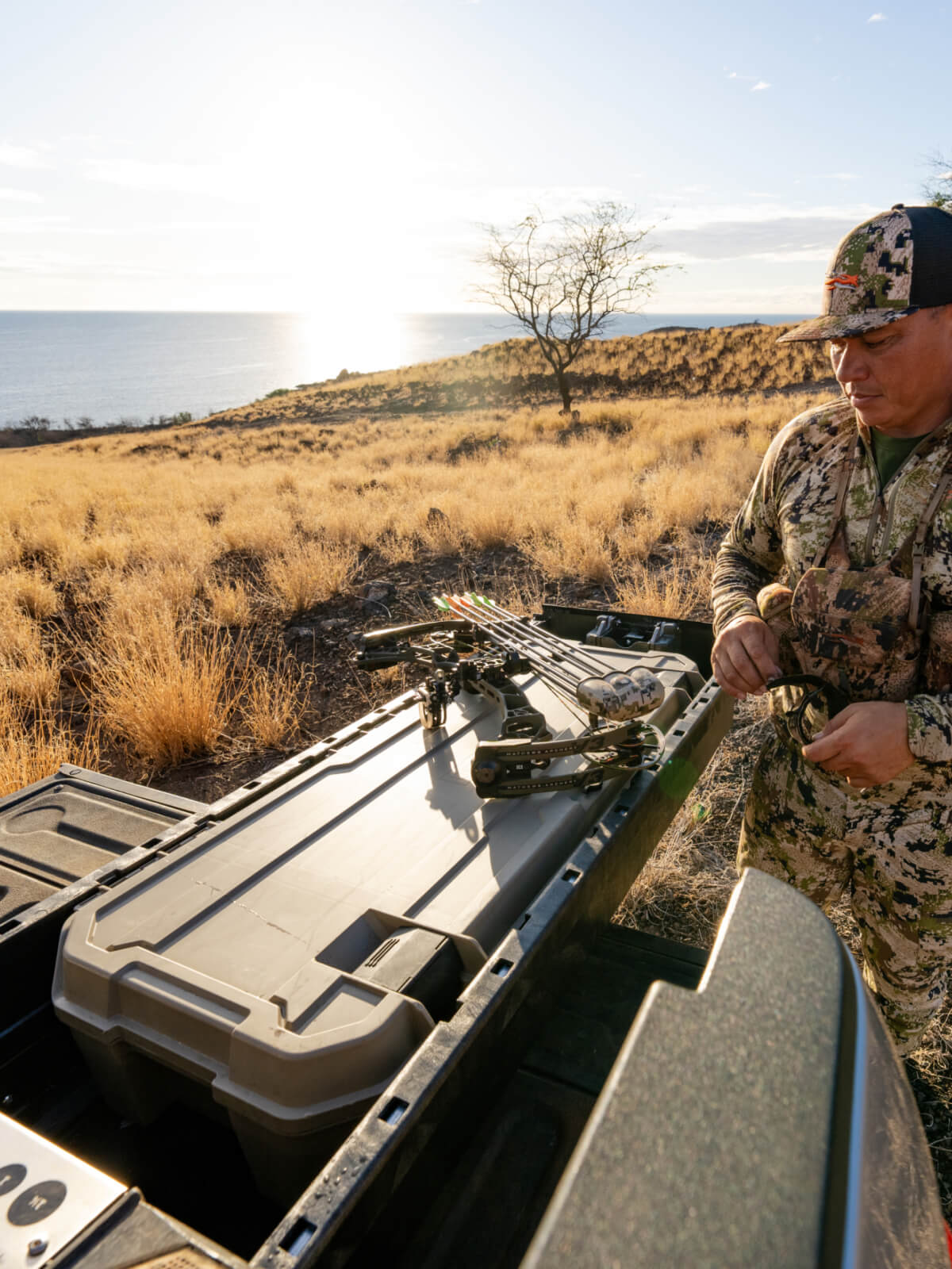 A man in camo retrieving his hunting bow from his Minuteman D-co Case inside of his DECKED Drawer System.