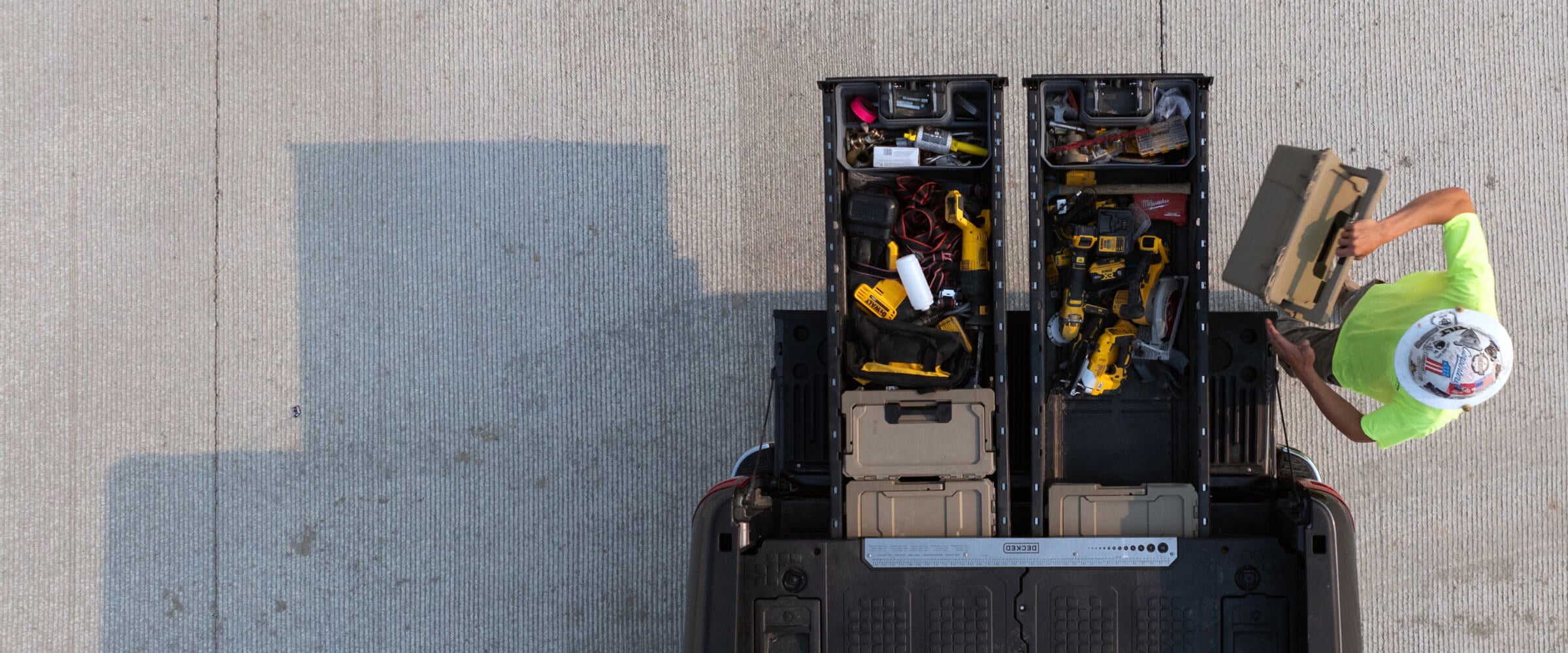 A bird's eye view of a man removing a sixer d-co case from his drawer system loaded with power tools.