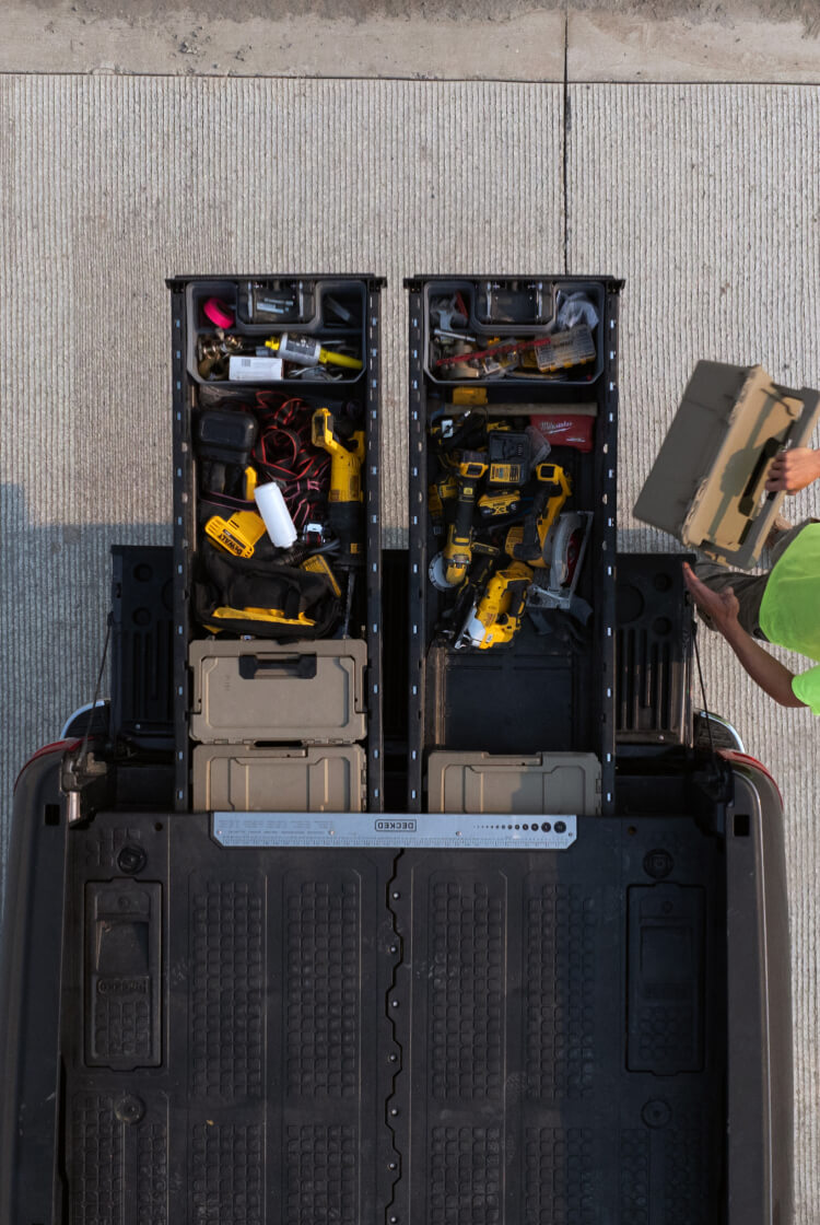 A bird's eye view of a man removing a sixer d-co case from his drawer system loaded with power tools.