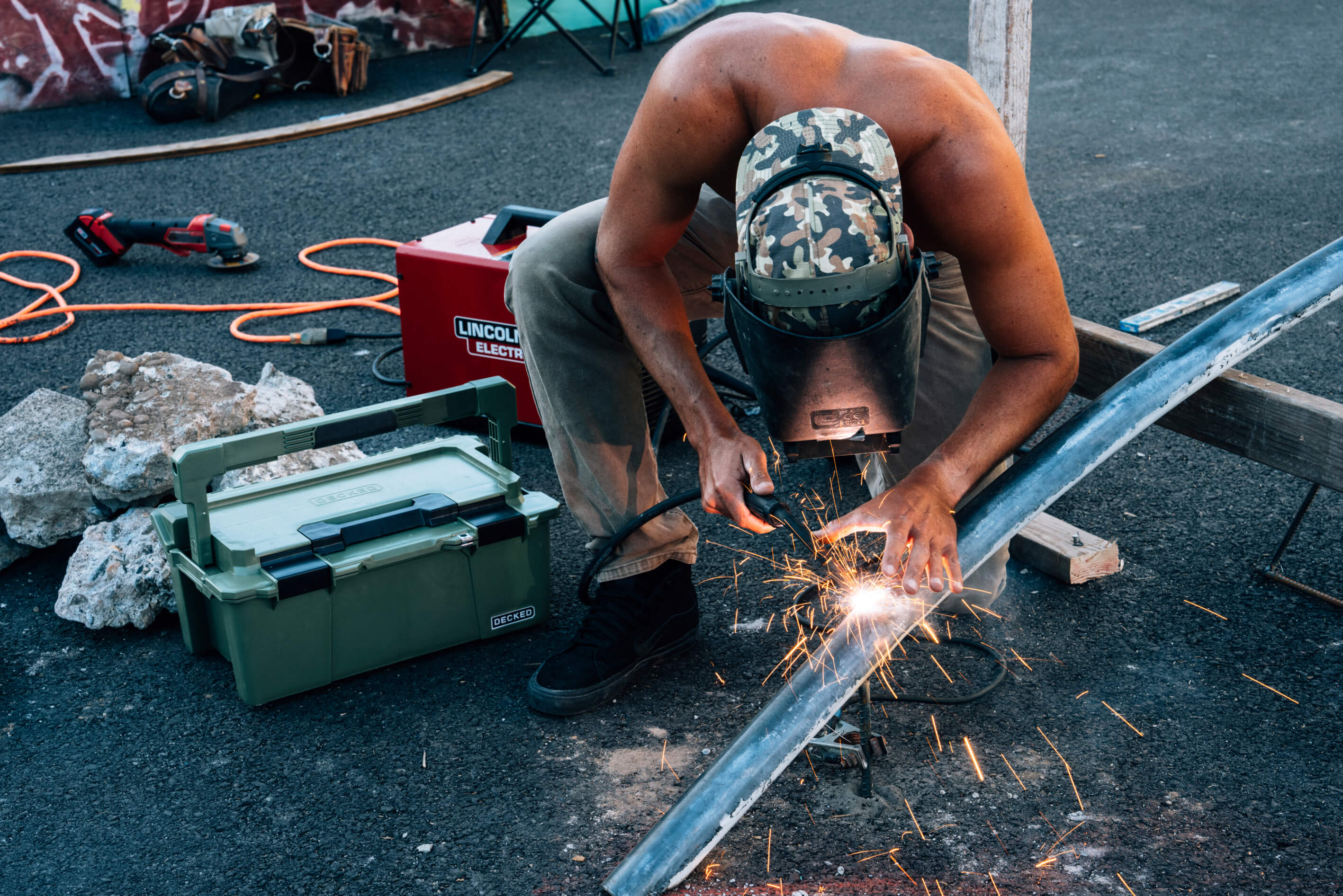 Person welding metal with sparks in an outdoor setting