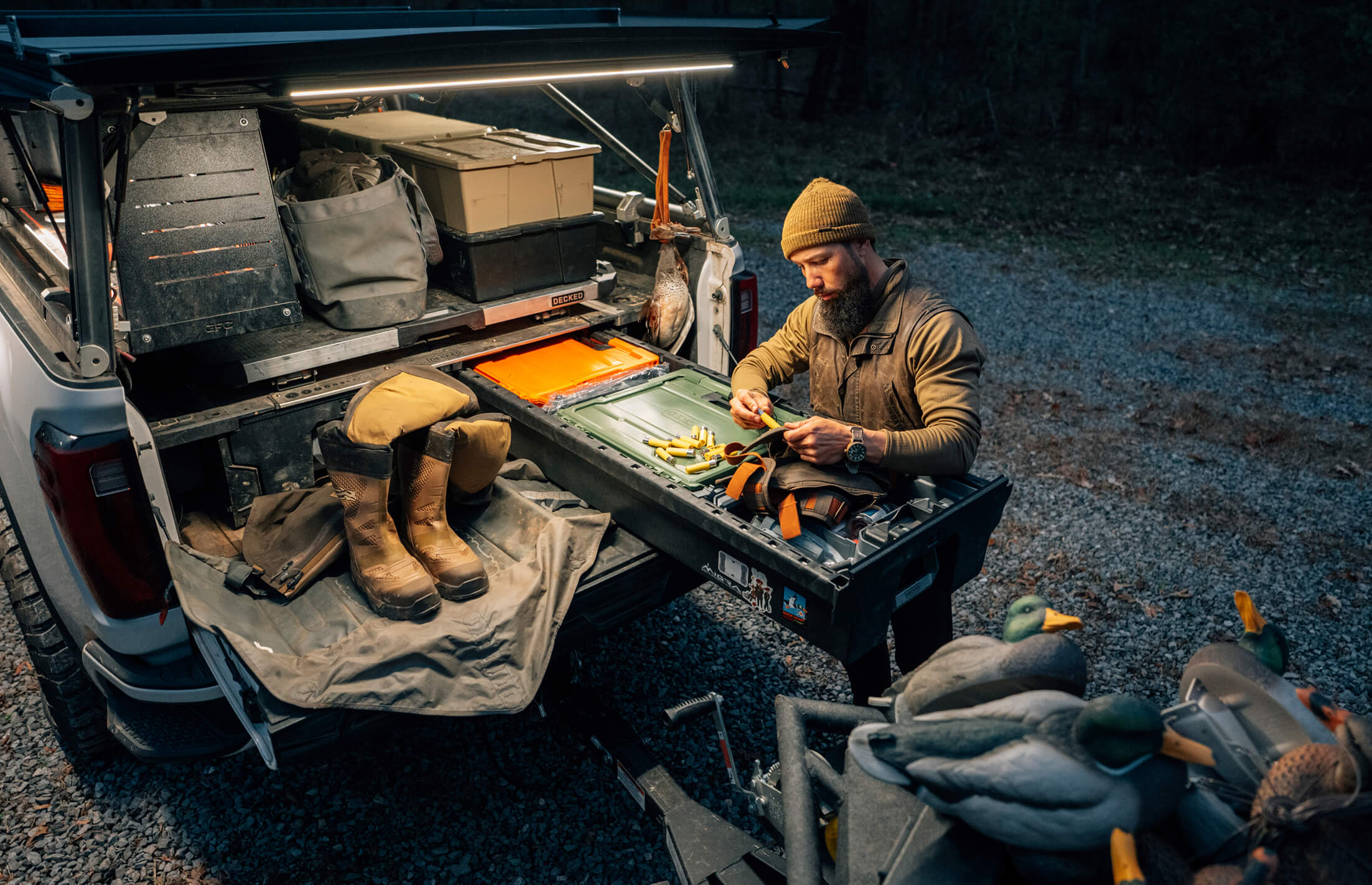 Man preparing food outdoors next to a vehicle with hunting gear