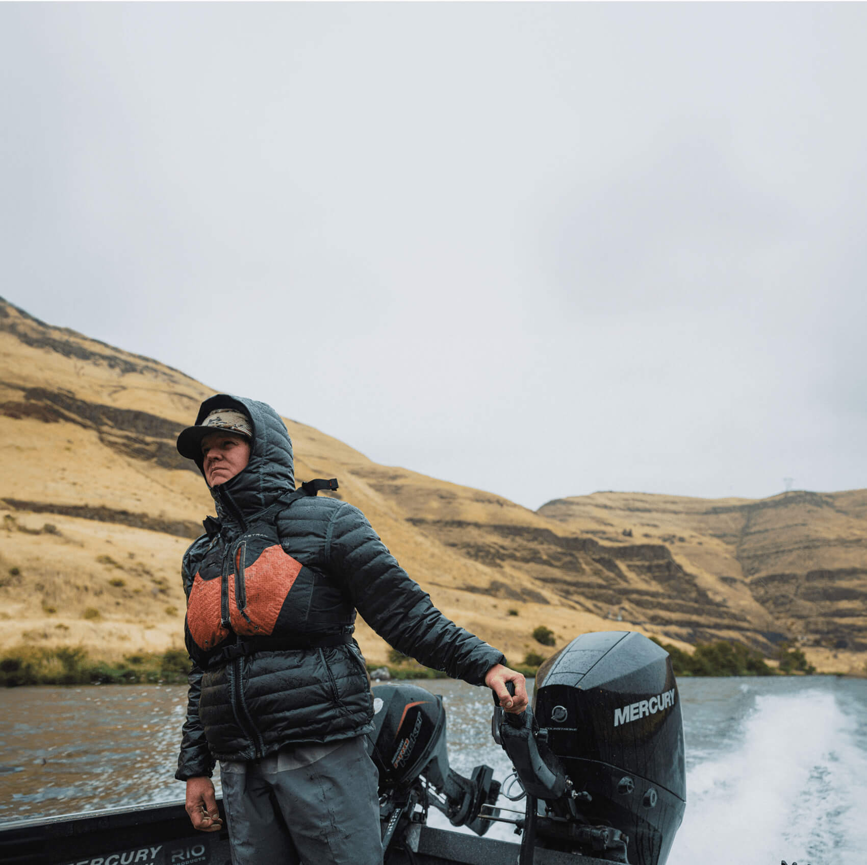 Person standing on a boat with a mountainous landscape in the background