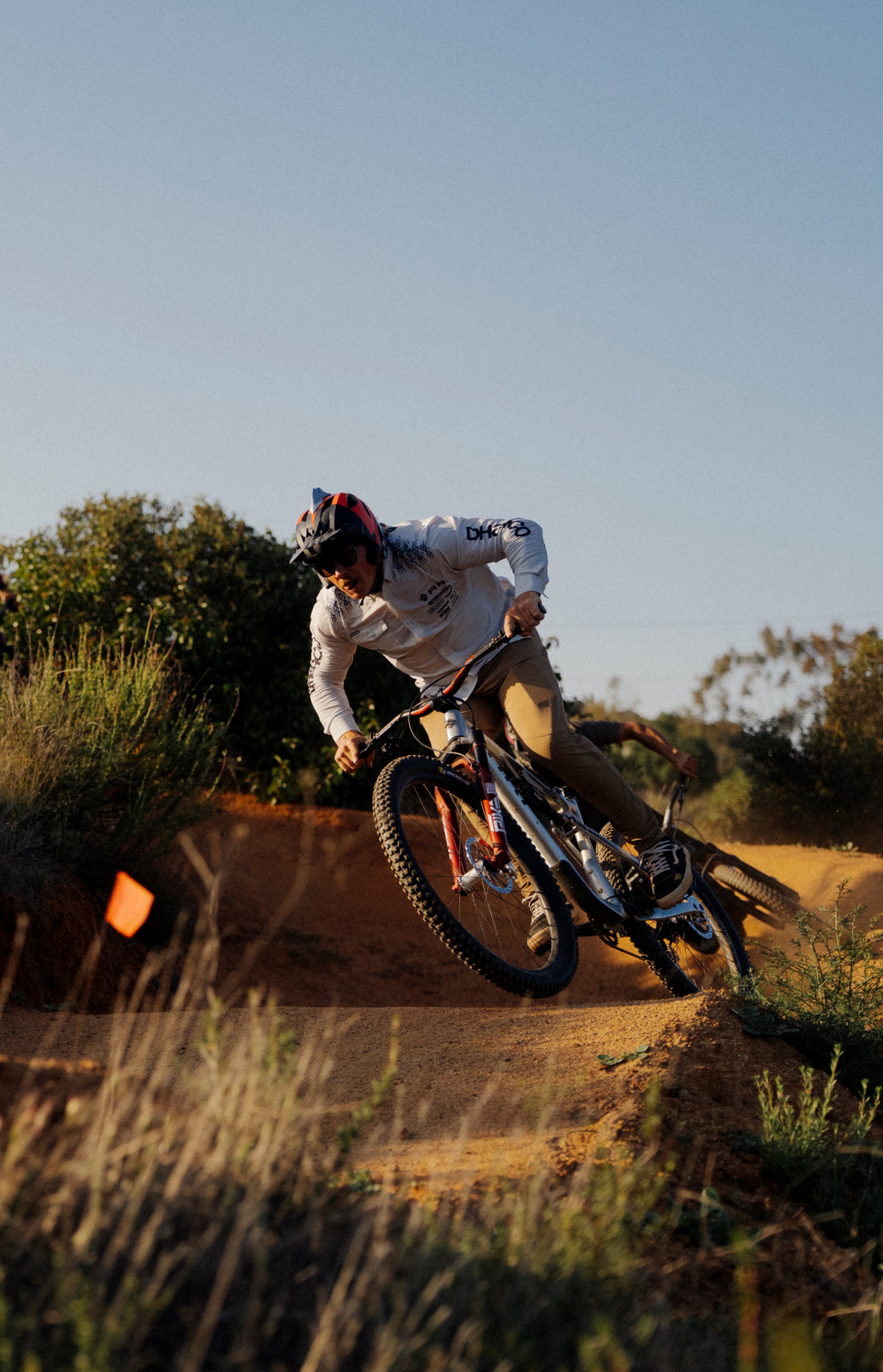 Kyle Strait riding a mountain bike on a dirt trail with trees in the background