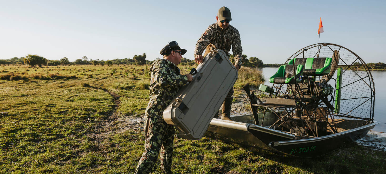 Two men loading a tan Minuteman into their airboat