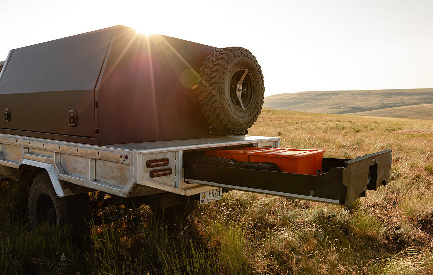 Land Cruiser outfitted with DECKED drawer system and orange halfracks in a grassy field.
