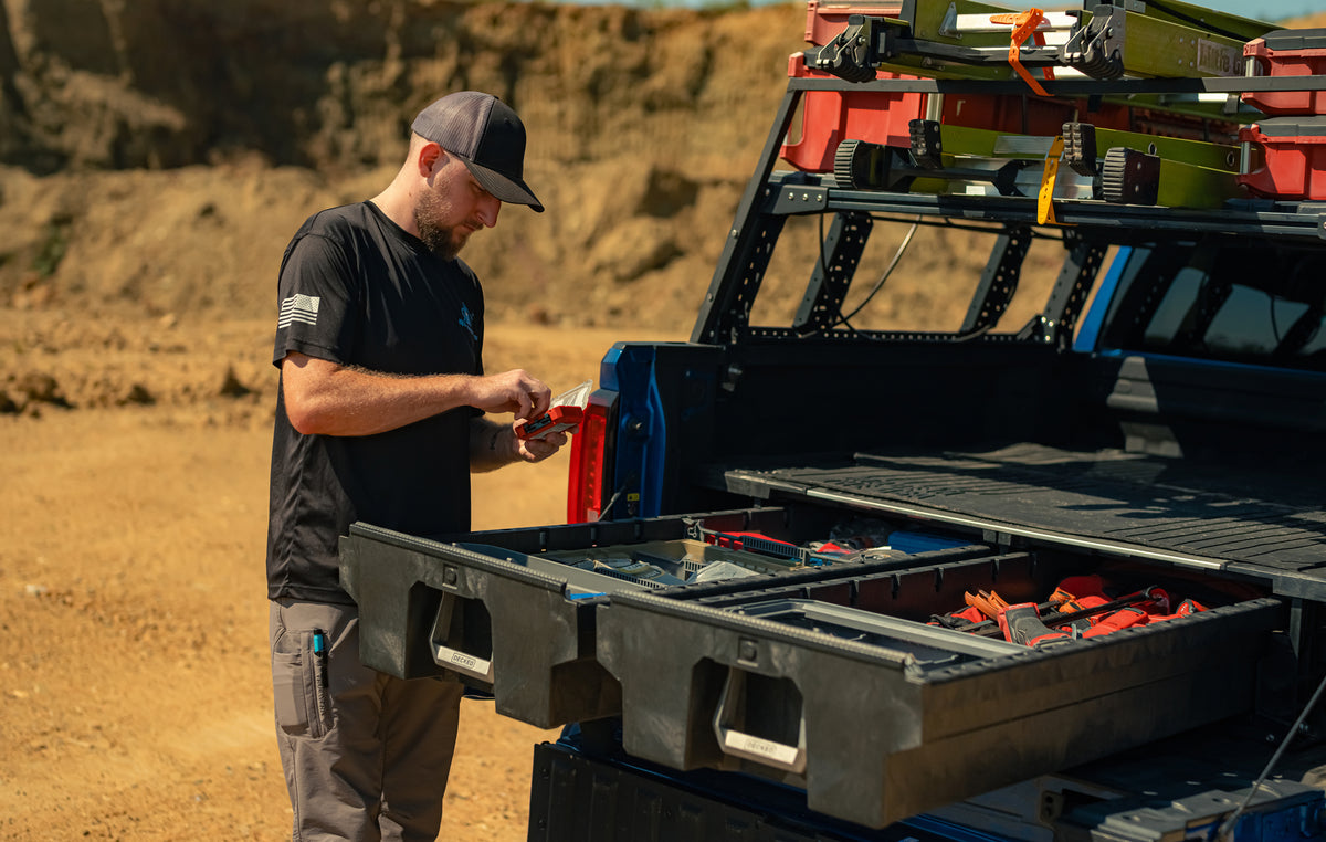 Thor Rippey stands beside his blue truck, sorting tools in the open DECKED drawers.