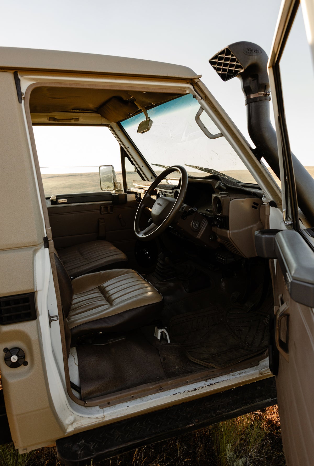 Interior view of a 1999 Toyota Land Cruiser, showing the driver and passenger seats, steering wheel, dashboard, and raised snorkel intake.