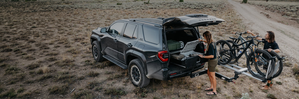Lifestyle image of two people gearing up for their biking adventure with their Toyota 4runner loaded with a DECKED drawer system.
