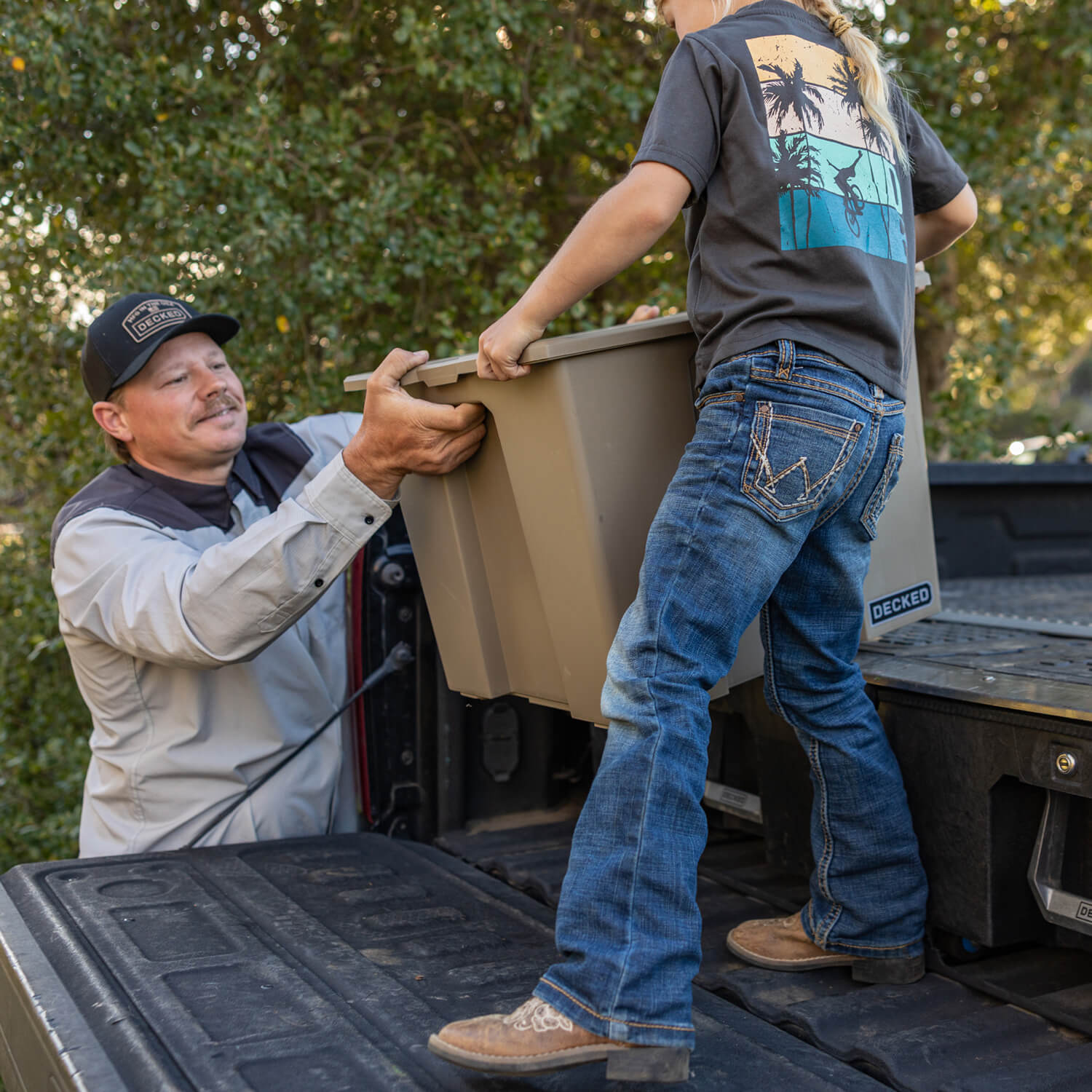 A man and his daughter unloading a DECKED Payloader 64 from the tailgate of a truck with a Drawer System in the bed.