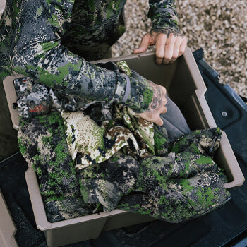 Person in camouflage gear organizing items in a Desert Tan Payloader 32 outdoors
