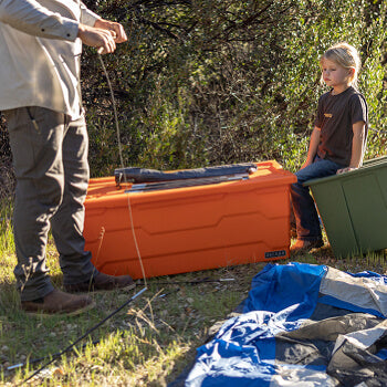 Person and child with orange and green Payloader storage containers in a natural setting