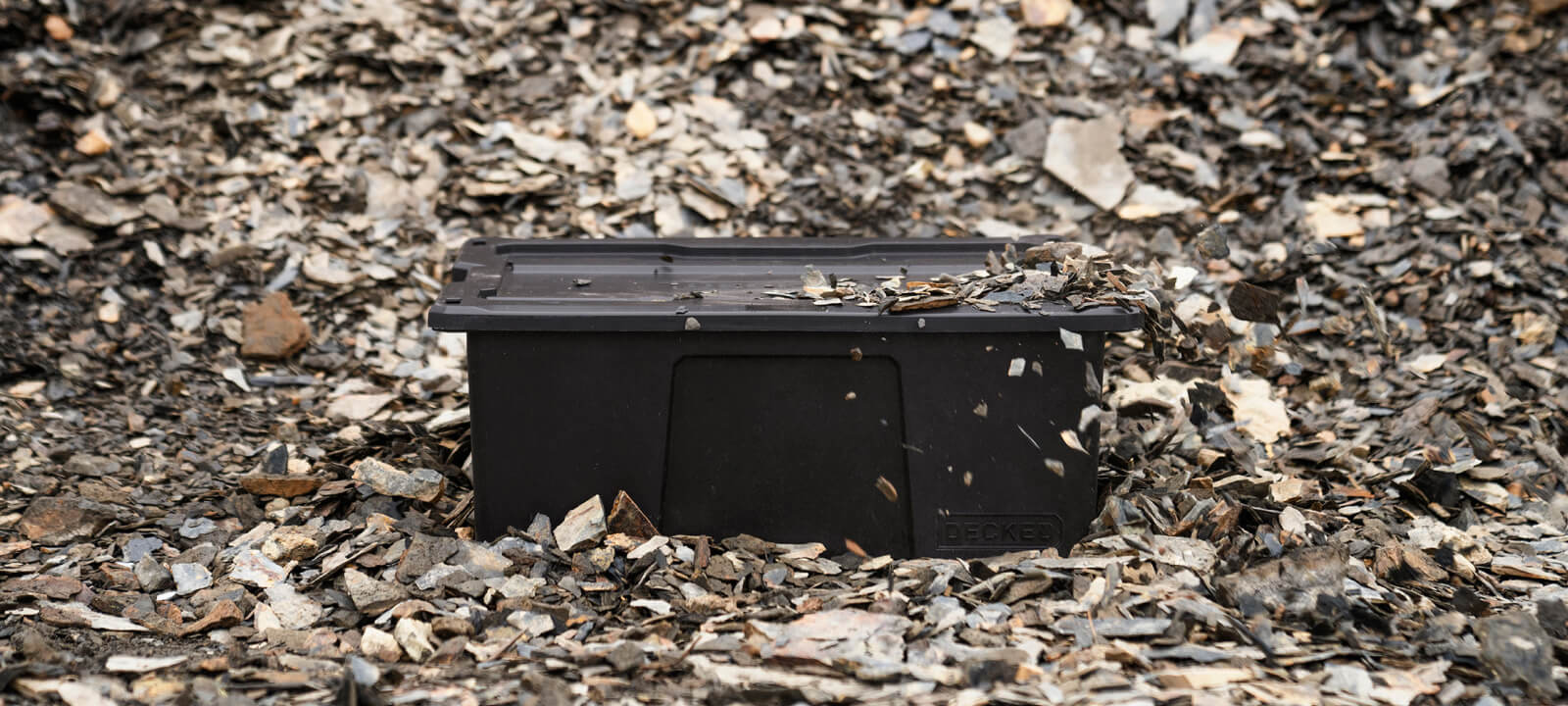 Black D-co bin sitting in gravel