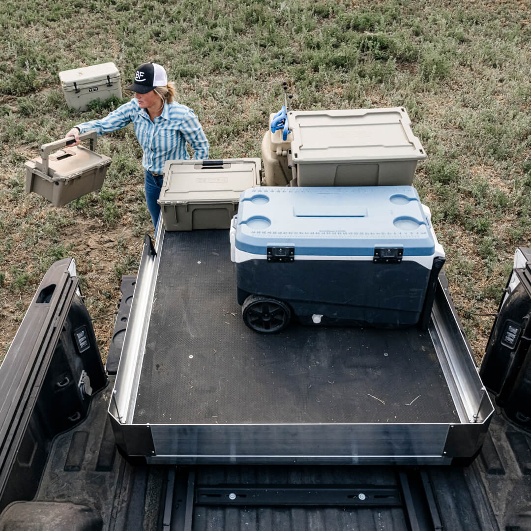 A woman rancher loading D-co cases onto her CargoGlide with high sides.