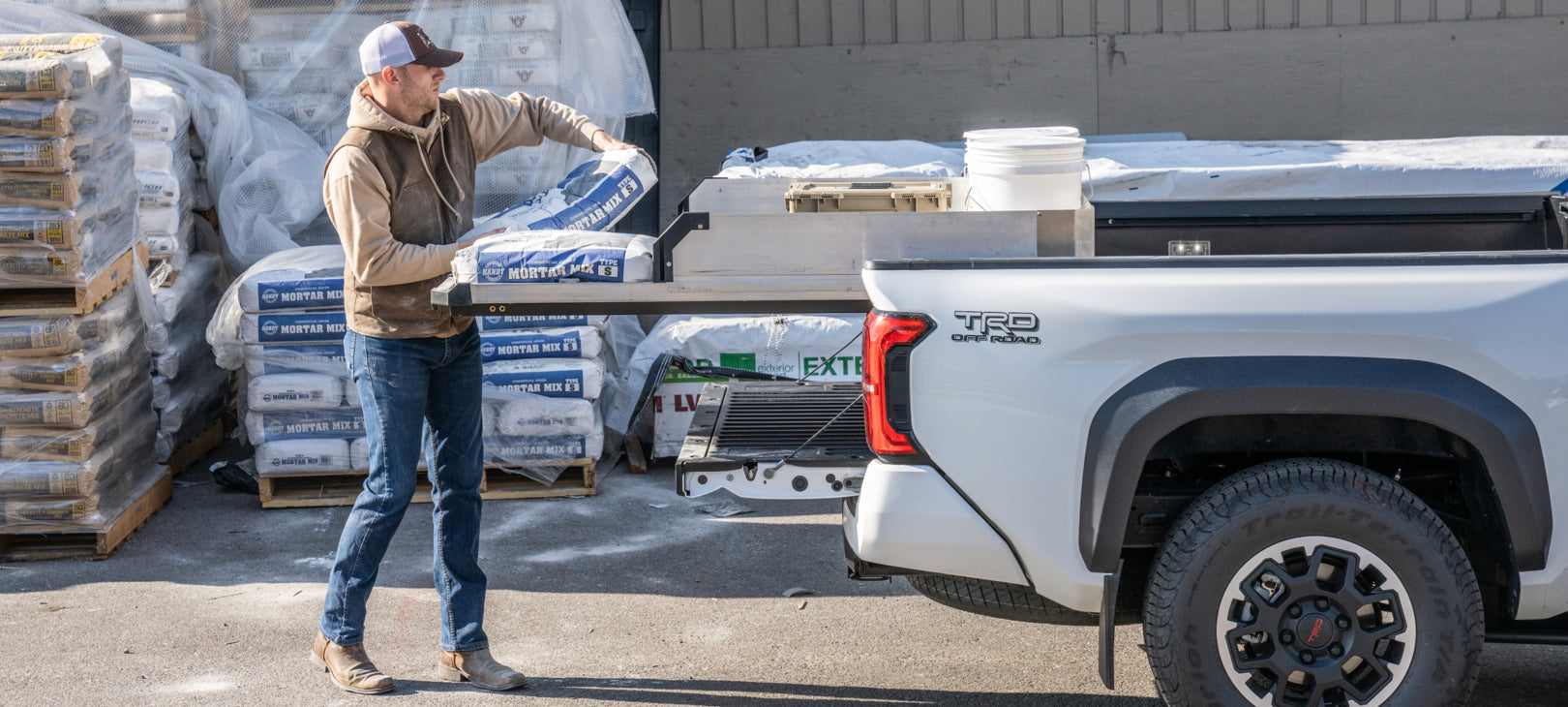 A man loading mortar mix bags onto his CargoGlide with High Sides.