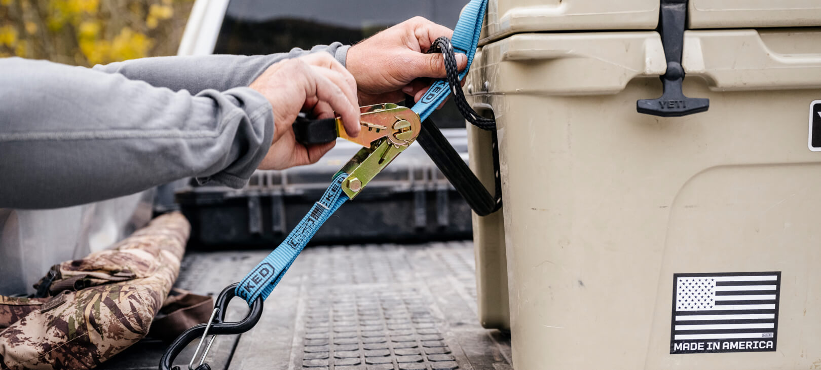 Blue ratchet strap being used to lash down a Yeti cooler.