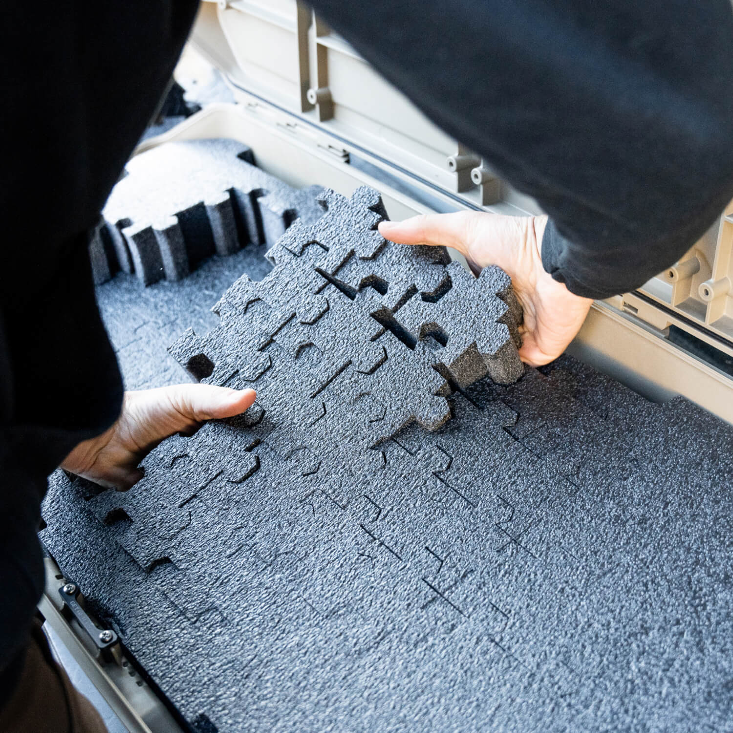 Someone taking out PuzzleFoam pieces from one of the layers in order to create the perfect foam fit around their expensive gear.