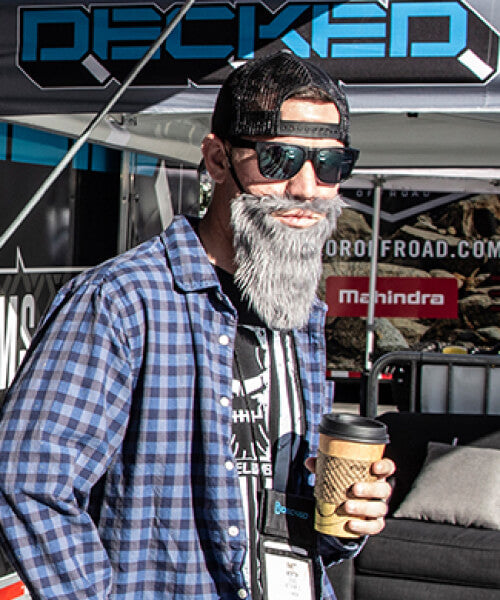 Man with a fake beard holding a coffee