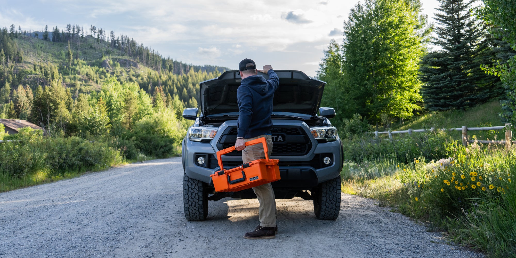 A man holding the Roadside OS Kit while he inspects what's under the hood of his truck.