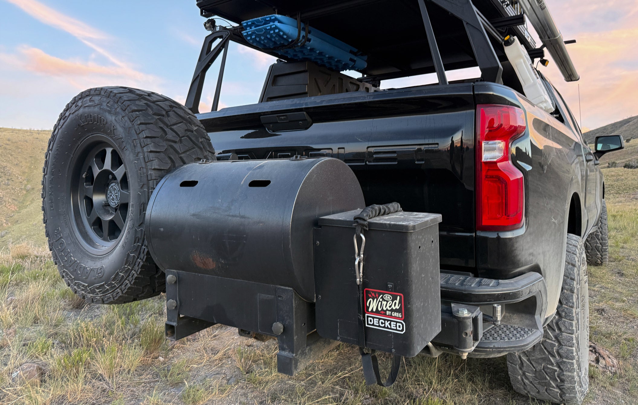 Black outdoor kitchen unit attached to a pickup truck in a natural setting