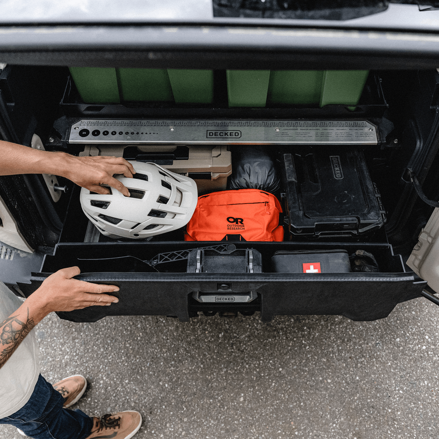 A man stowing his bike helmet in the drawer of his DECKED System for Ford Bronco.