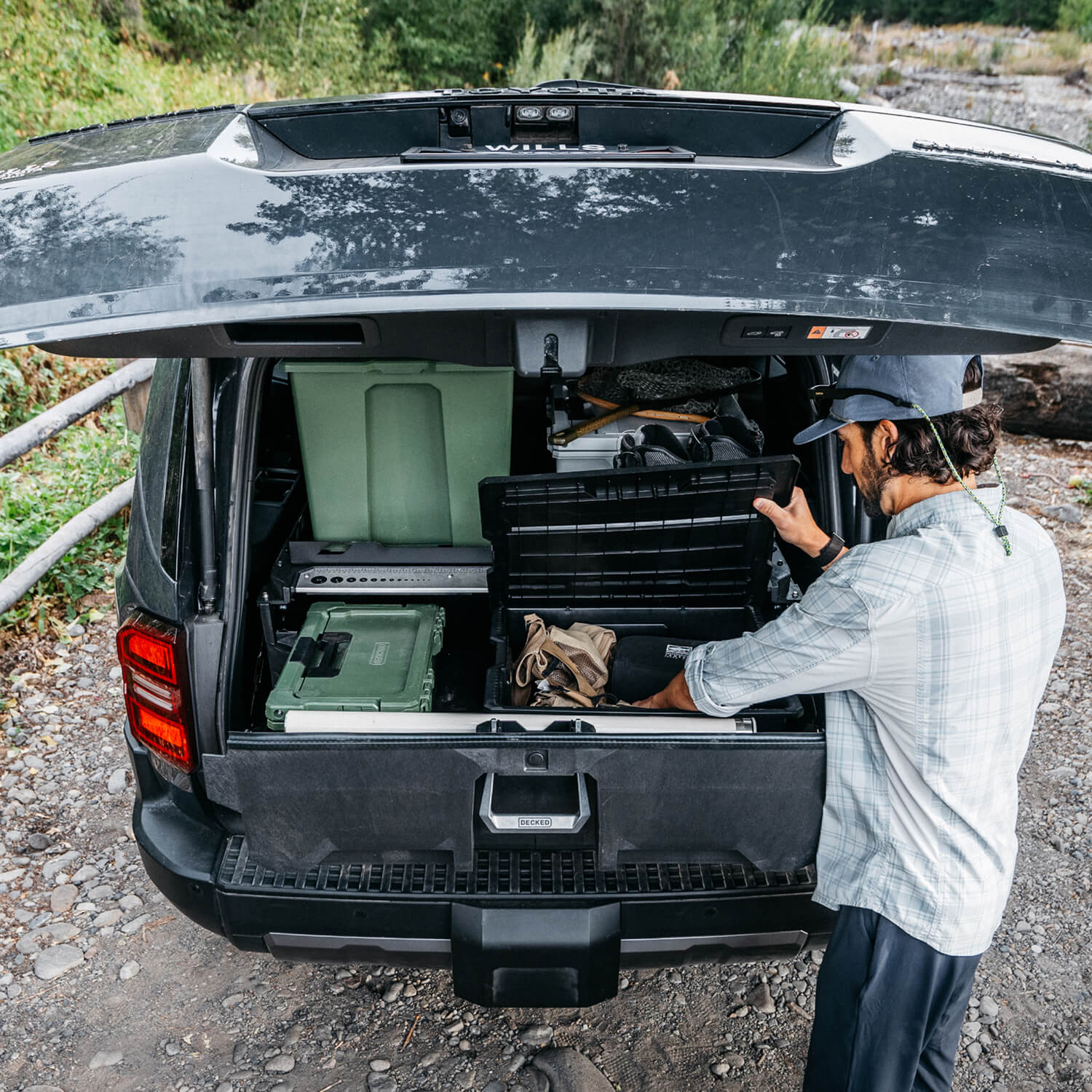 A man retrieving fishing gear from the protective cases inside of the DECKED Drawer System for his 6th Generation 4Runner.