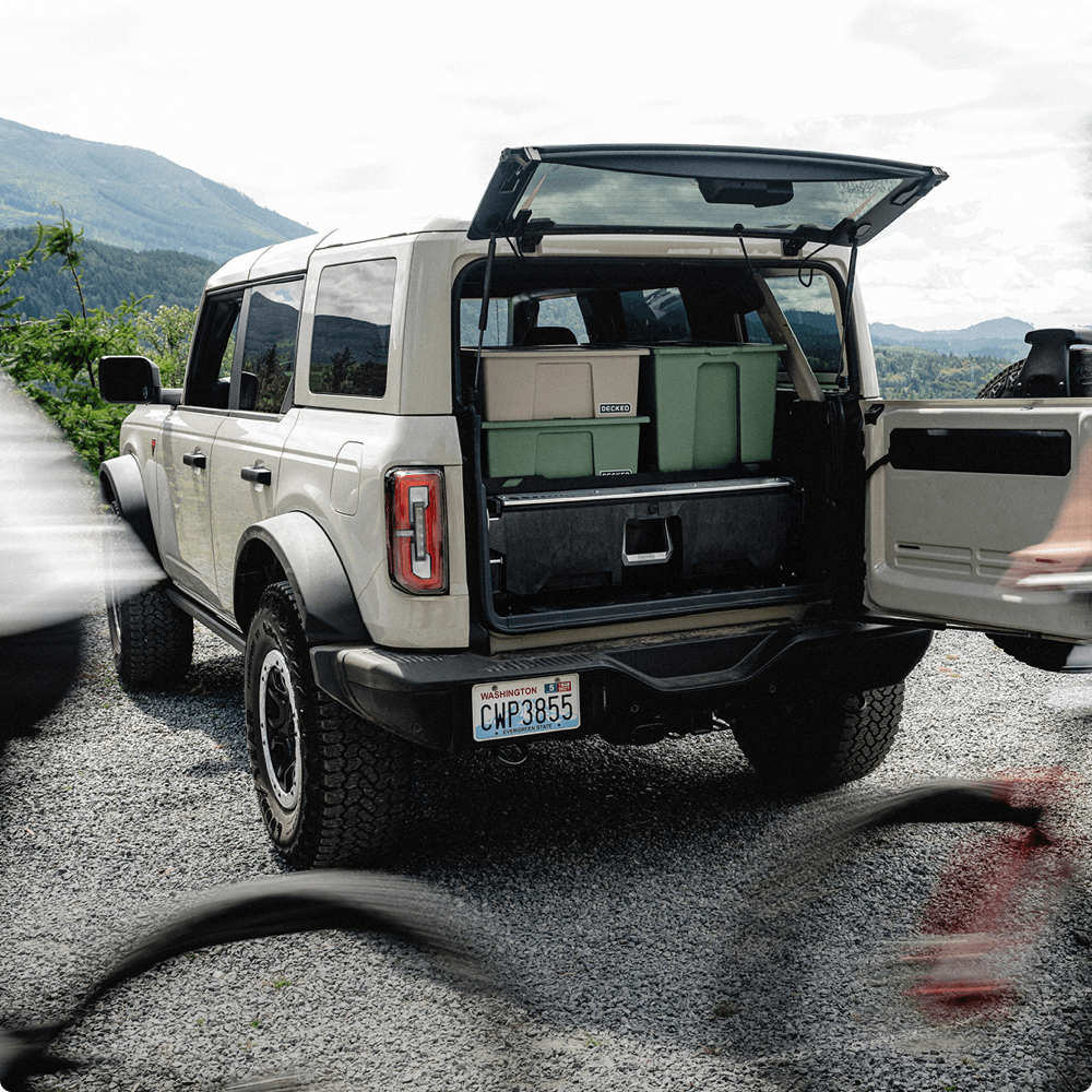 A DECKED Drawer System with DECKED cases and bins stacked on top in the back of a Ford Bronco up in the mountains.