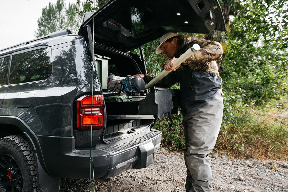 A man retrieving a fishing rod case from the inside of his DECKED Drawer System for his Toyota LandCruiser.