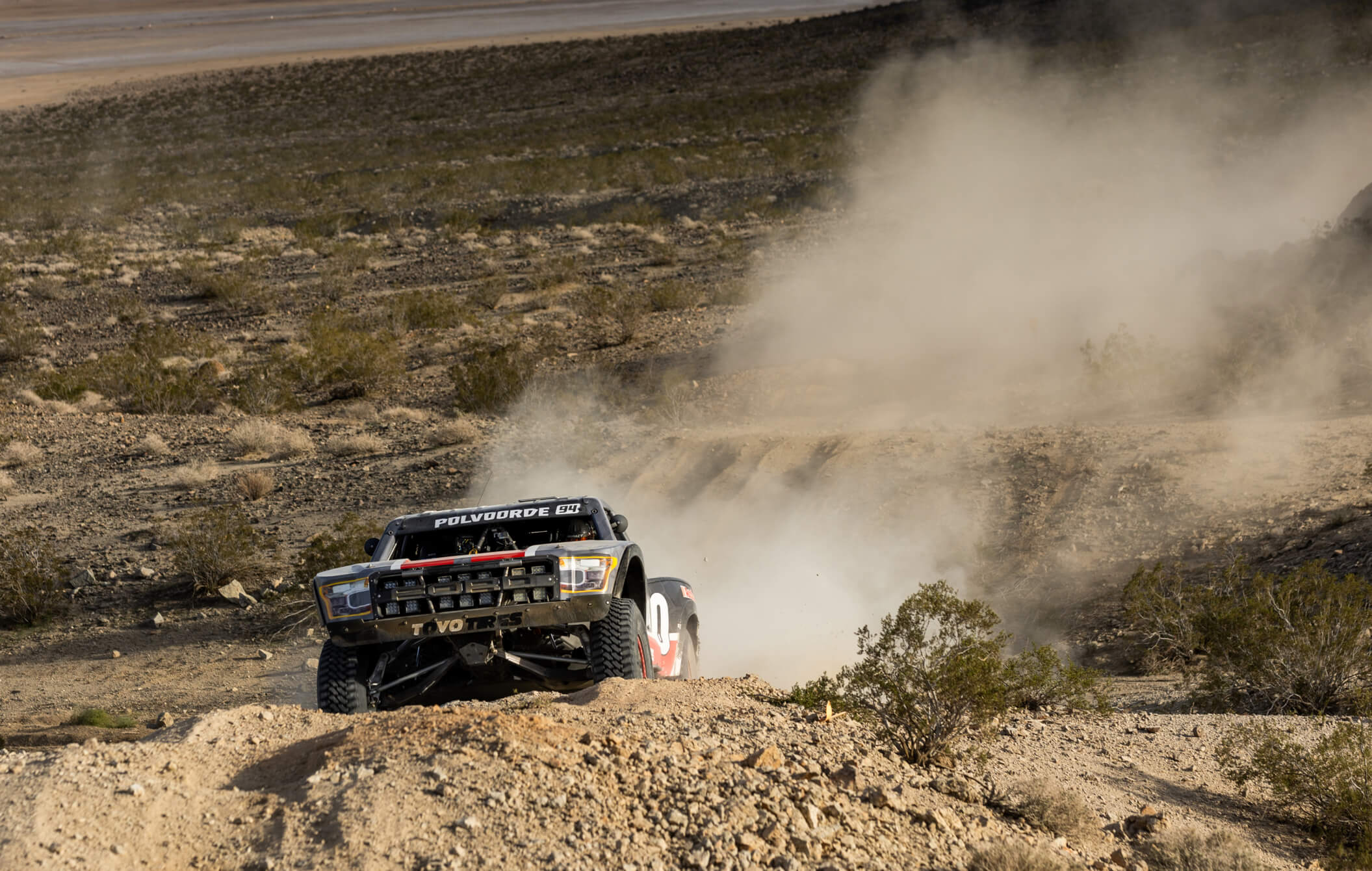 Chris offroad racing in the desert with dust flying behind his ford.