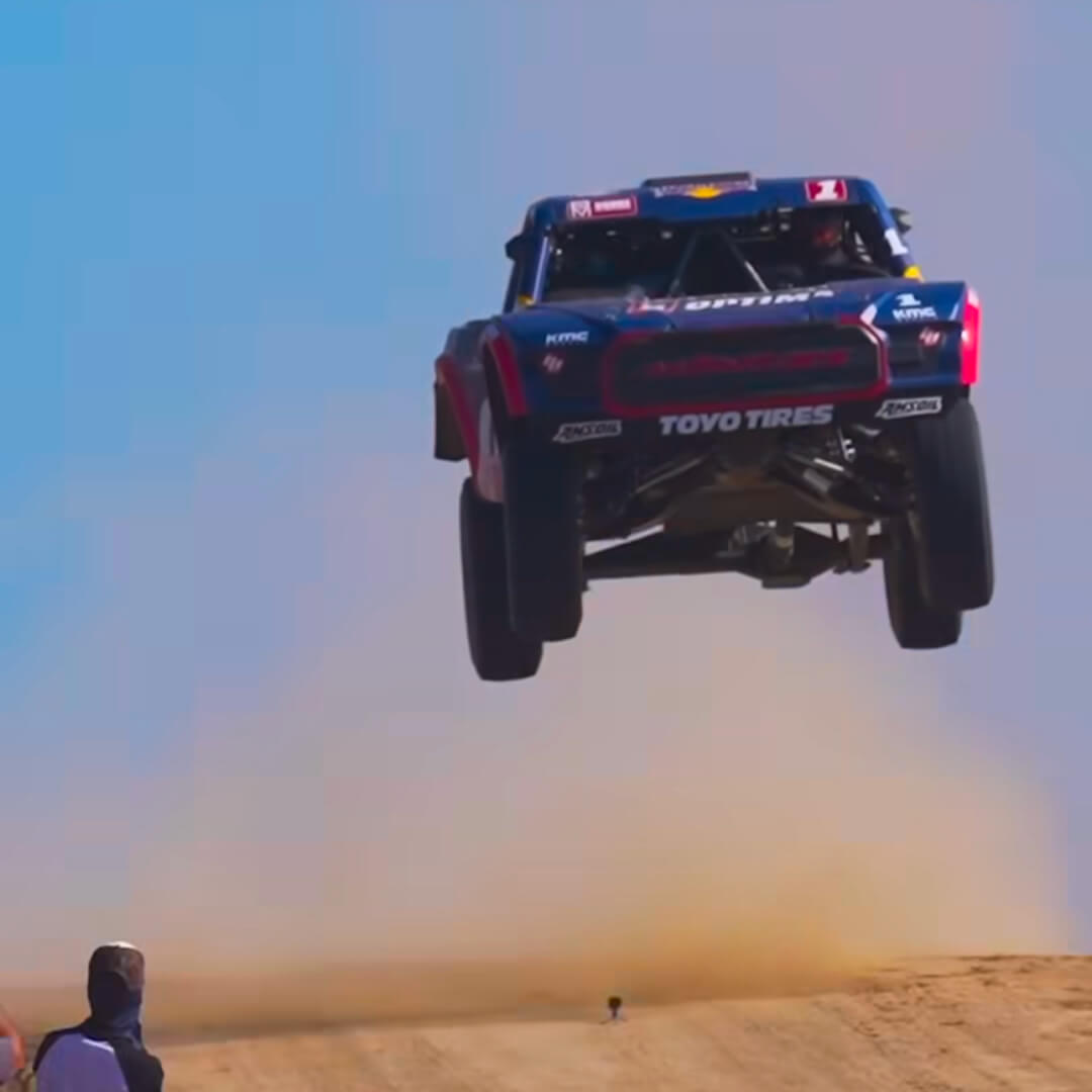 Chris flying through the air in a truck during a race in the desert.