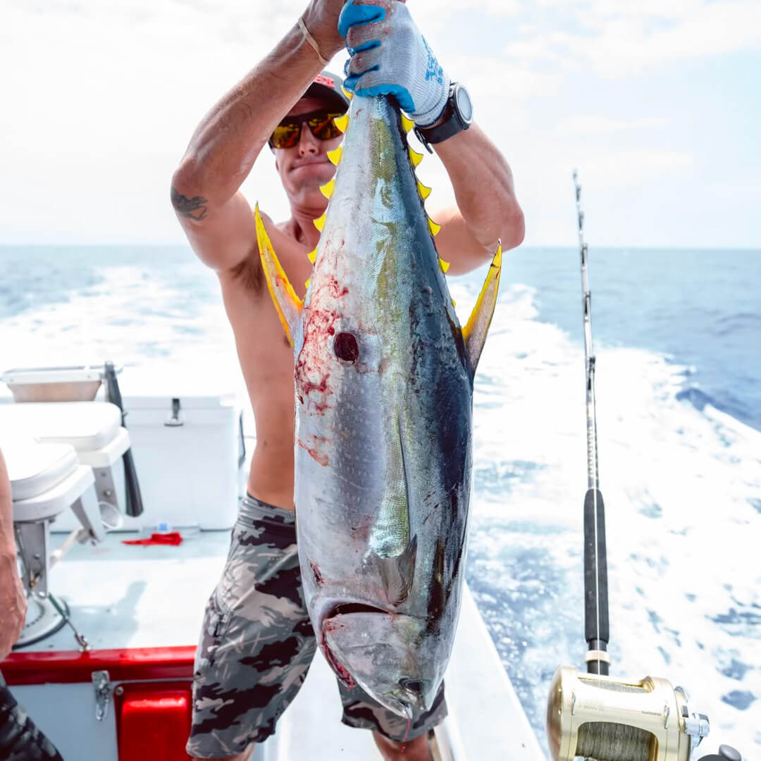 Danny Bolton holding a big 'ol tuna, his face is contorted from the effort of lifting the fish for the photo.