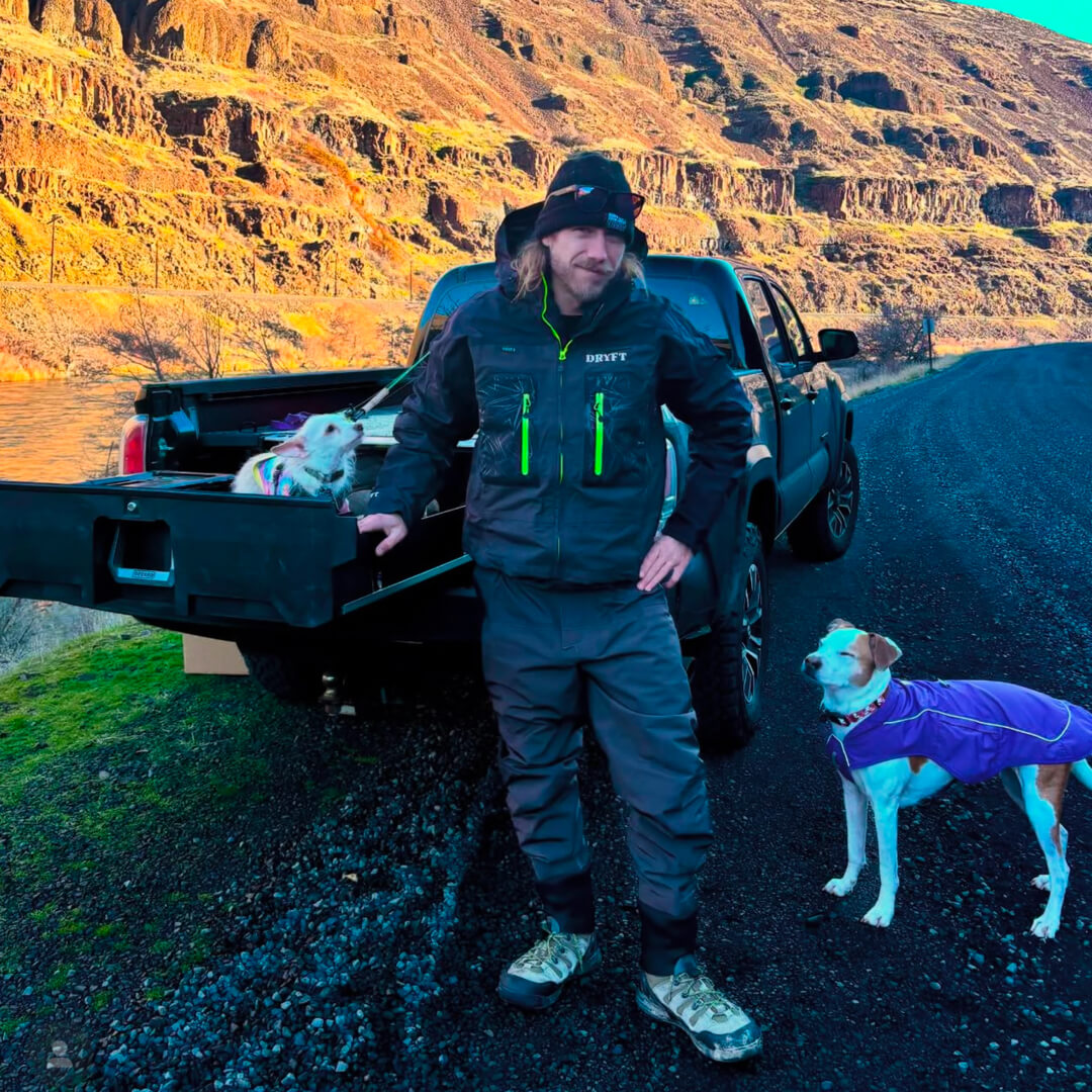 David Gravette standing next to his truck and Drawer System in a canyon with his two dogs.