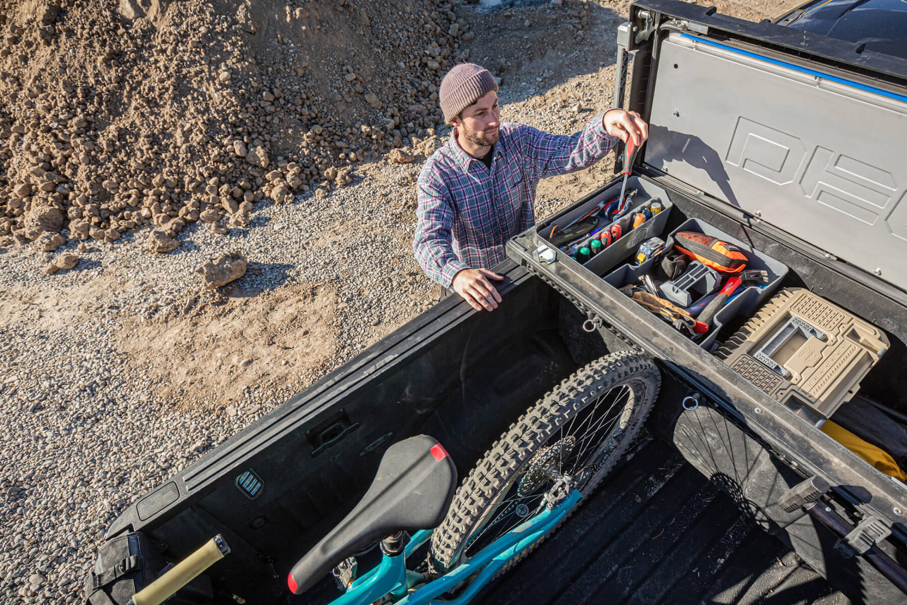 man accessing his tools in the back of a decked tool box