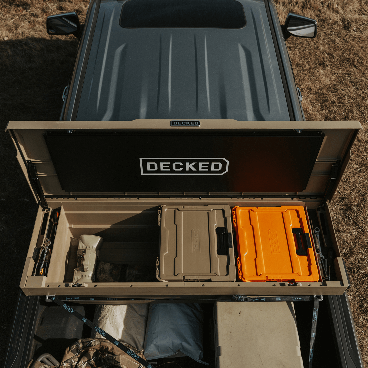 Open truck bed with 'DECKED' Tool Box storage system and various items inside.