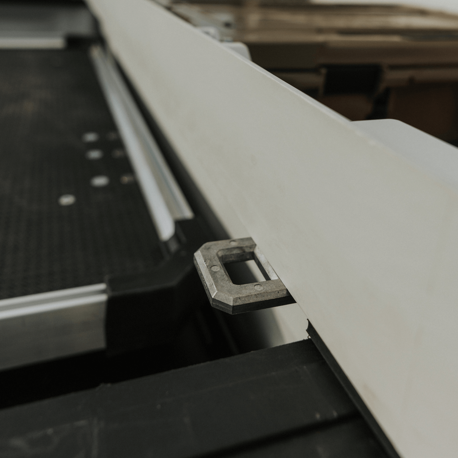 Metal D-ring Tie Down bracket mounted on a white Tool Box with a blurred background