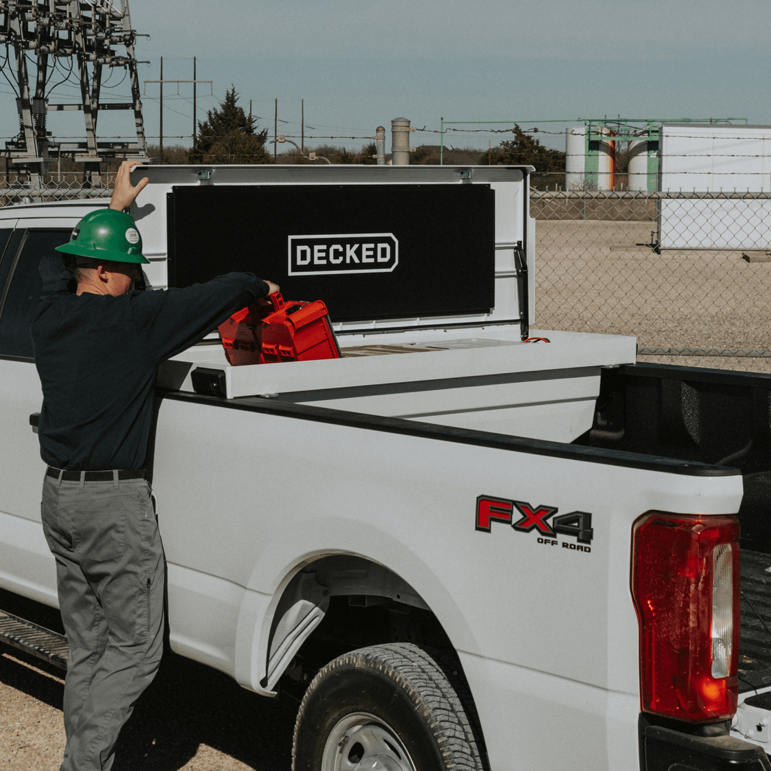 Person loading a truck with a 'DECKED' Tool Box in an industrial setting