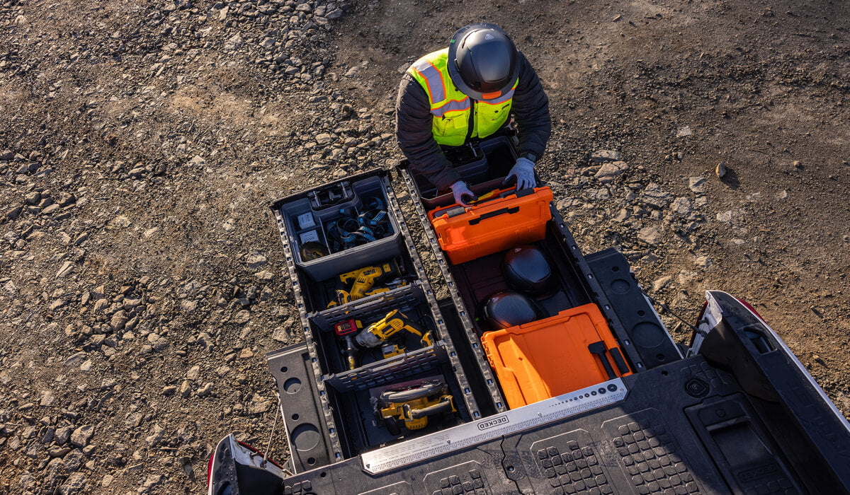 Person in high-visibility vest and helmet organizing his tools inside of a DECKED Drawer System on a construction site.