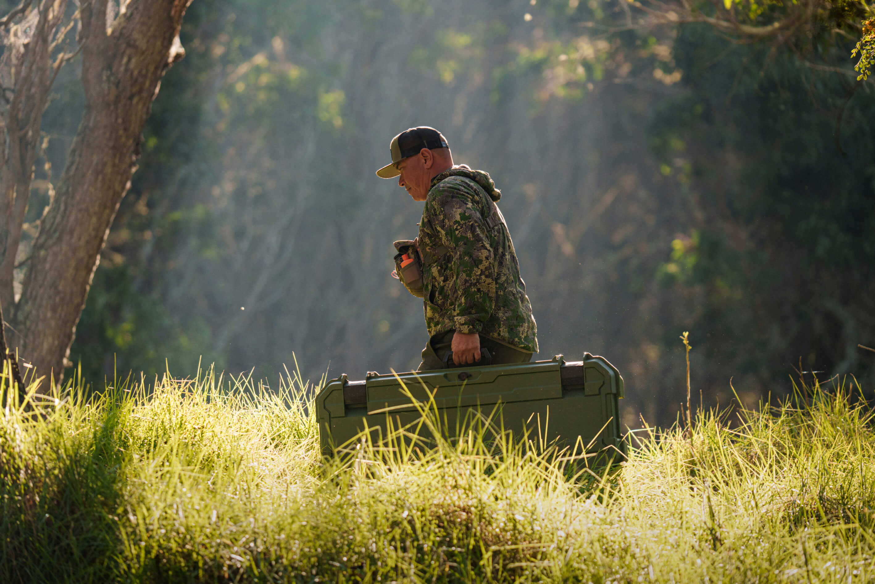 Man in camo carrying his Honcho 80 D-co bow case to his truck.