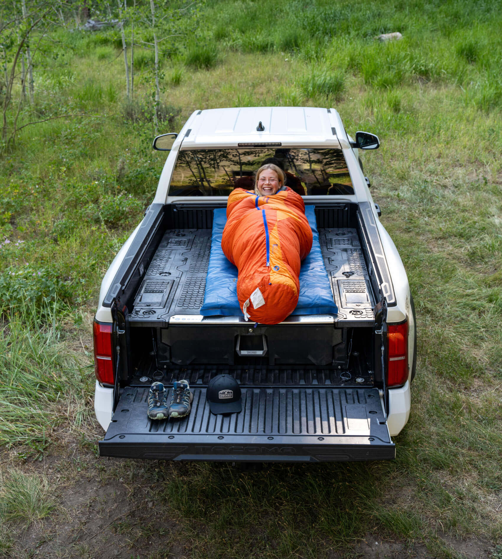 Person lying in a sleeping bag on top of a Drawer System in the bed of her truck.