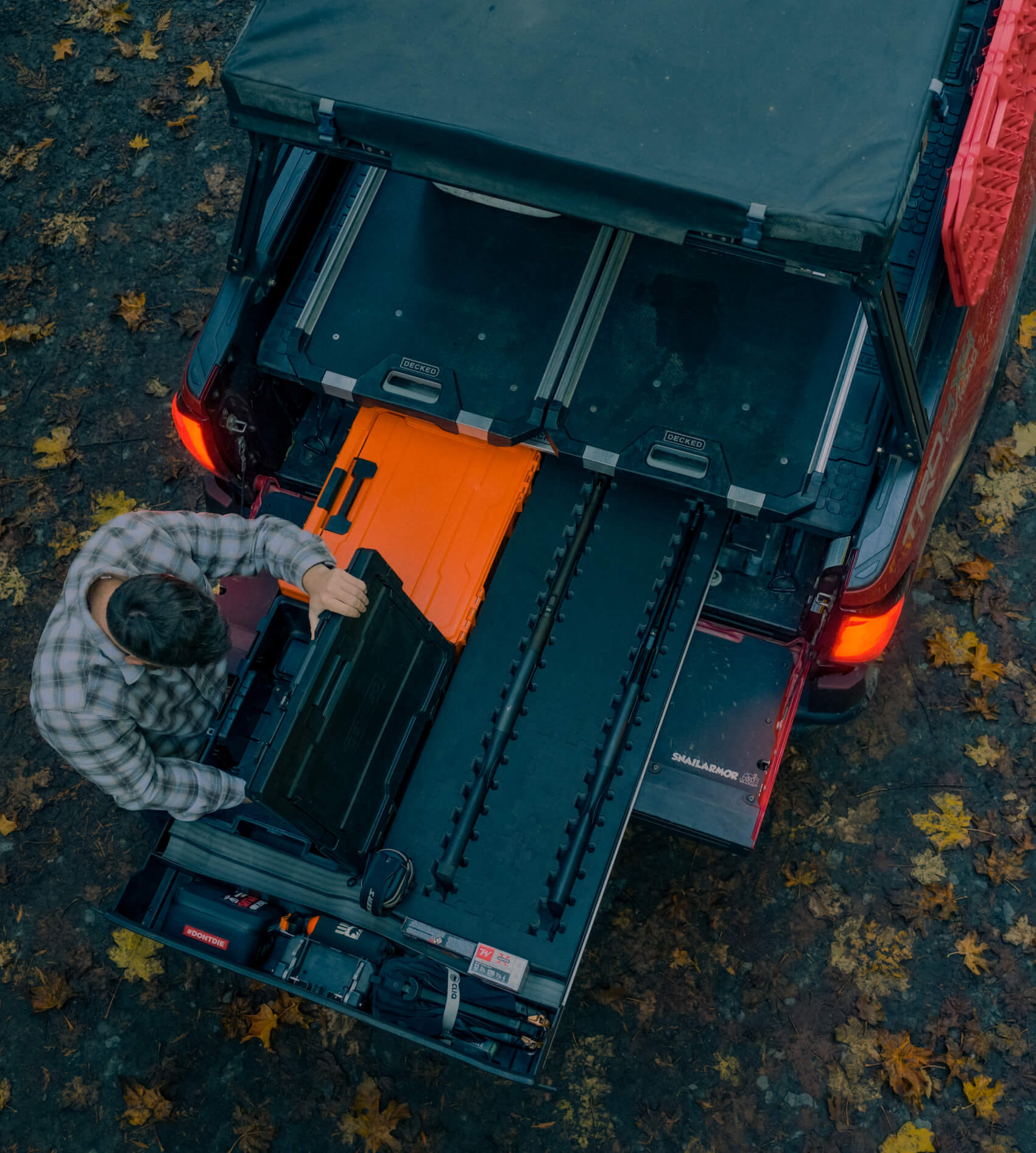 Person opening a black Halfrack D-co storage case inside of a Drawer System with autumn leaves on the ground.