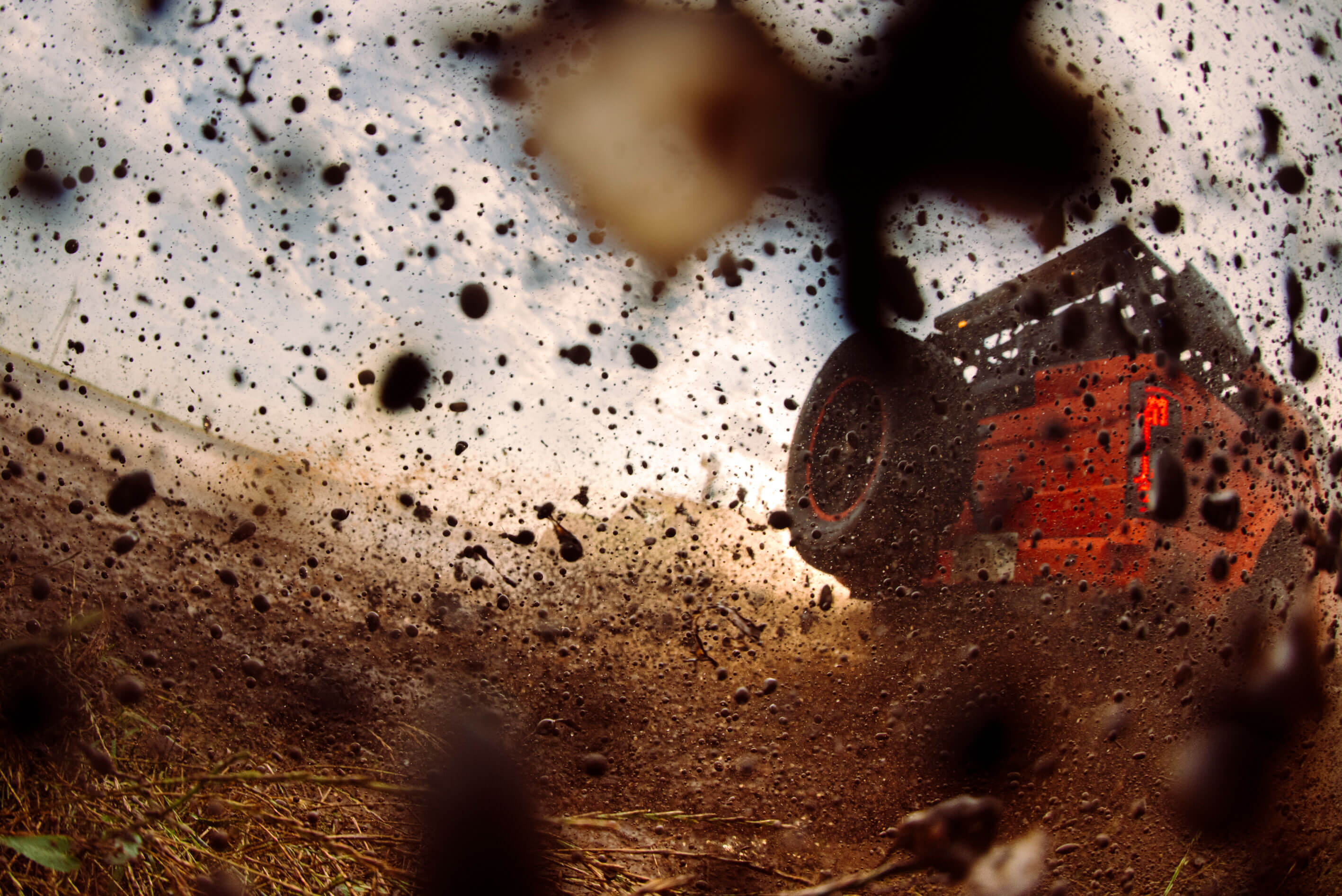 Close-up of a muddy tire with water droplets on a wet road surface