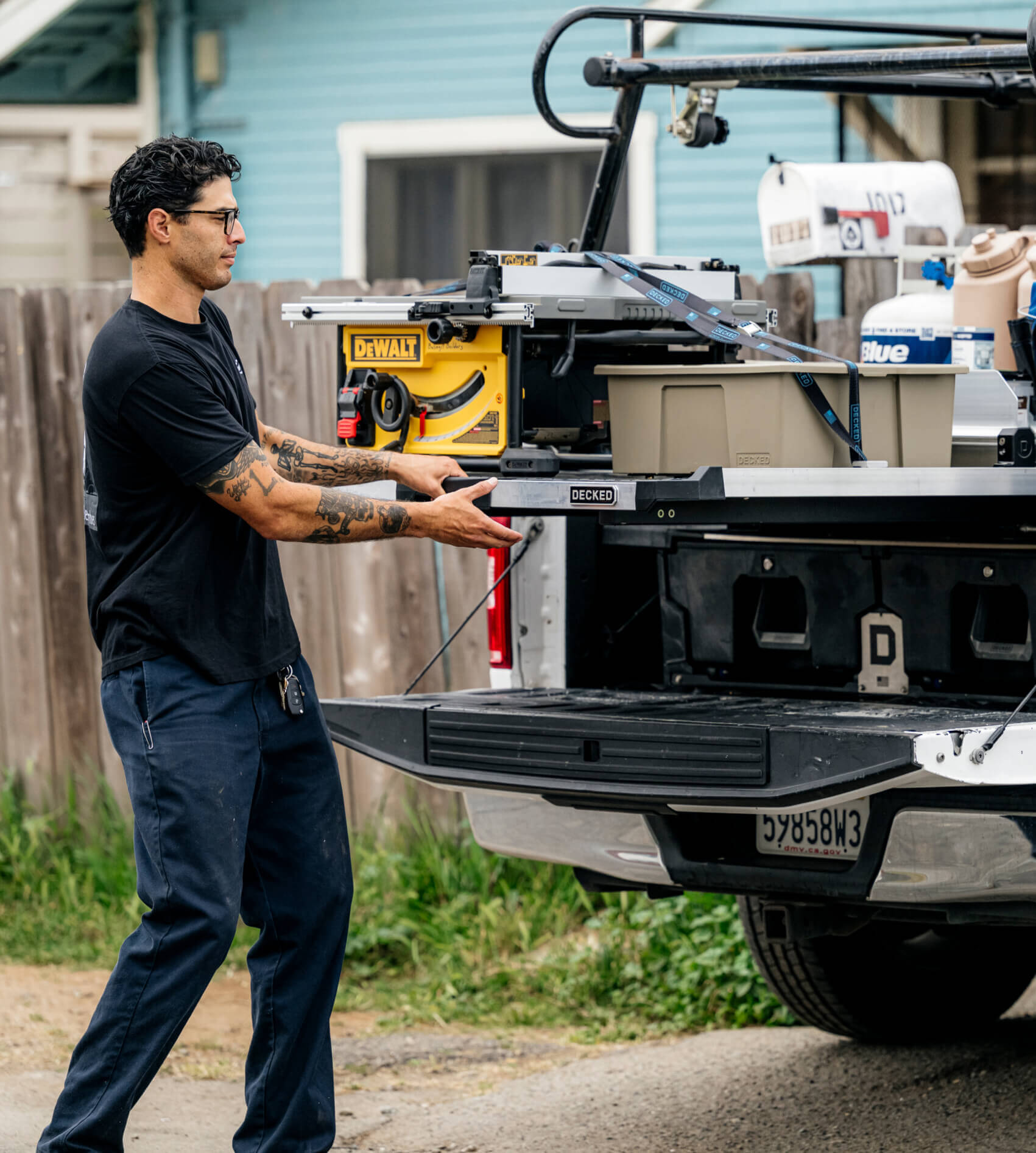 Man loading a Dewalt table saw into the bed of his truck using a CargoGlide sliding bed tray.