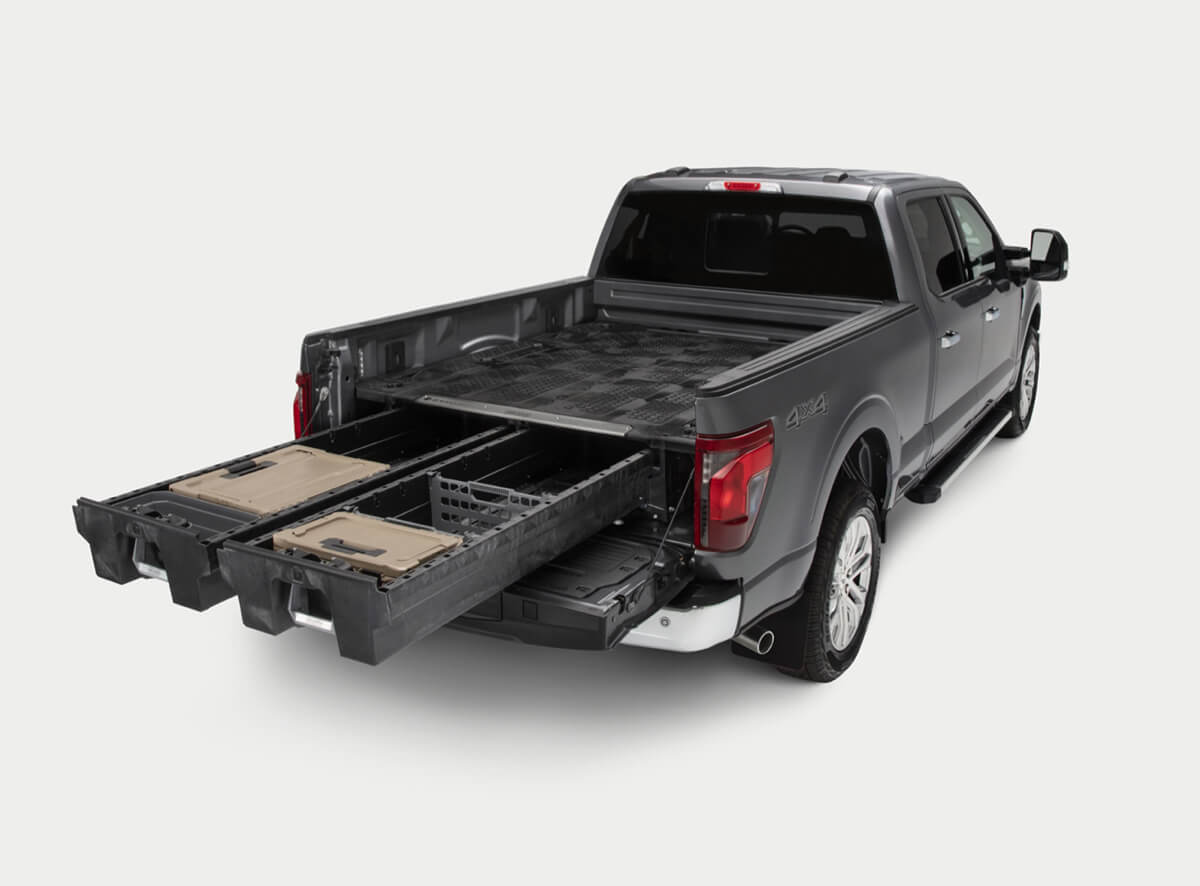 An open drawer system with 'DECKED' d-co cases in the bed of a Ford F-150.